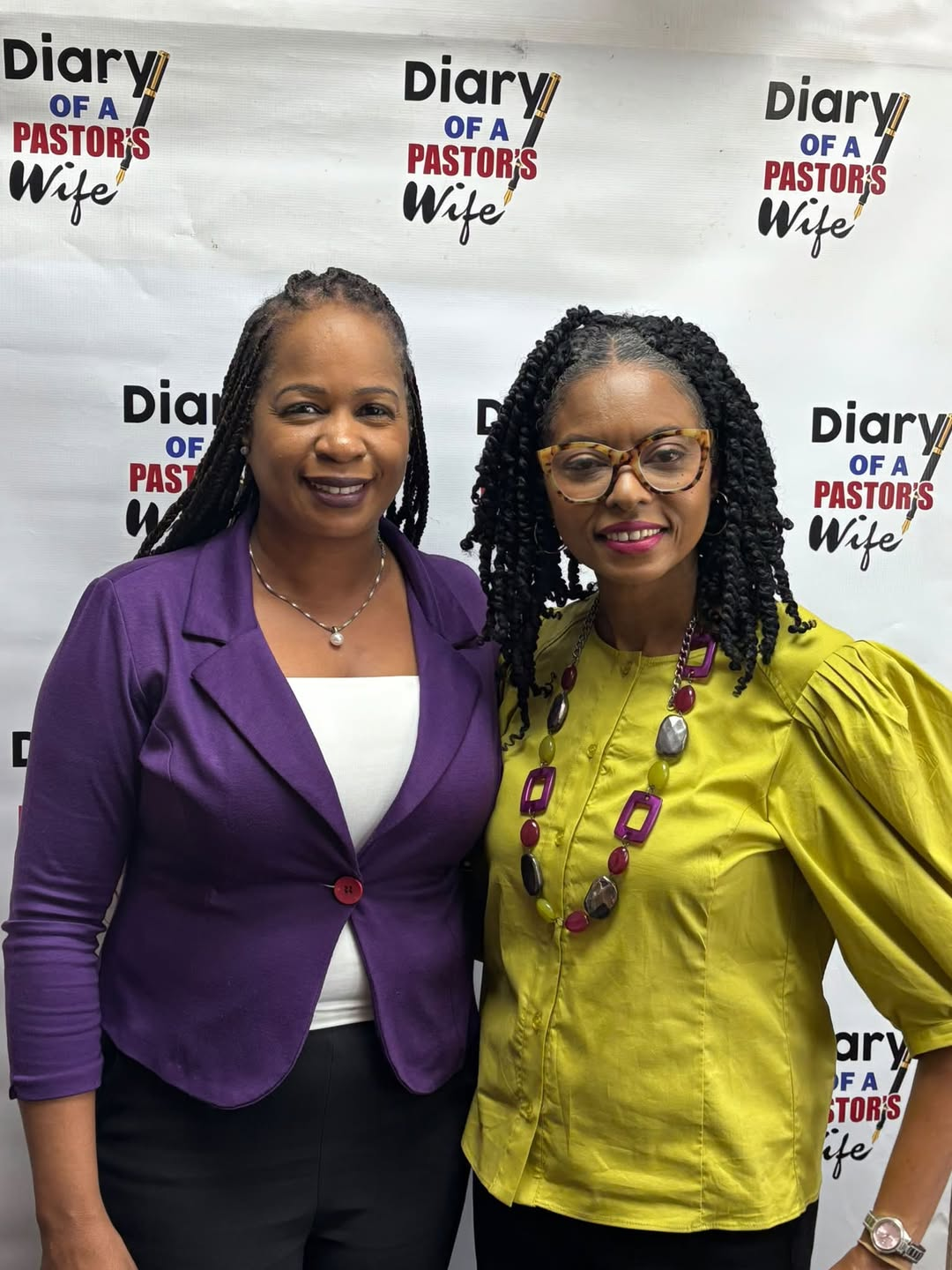 Two women smiling together in front of the Diary of a Pastor’s Wife backdrop