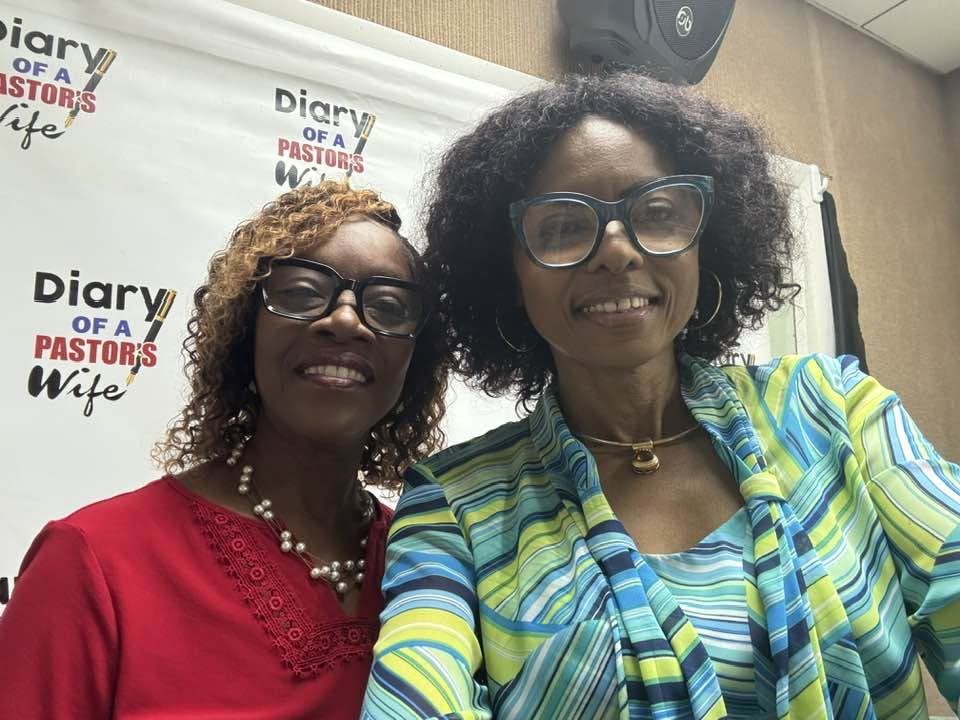 Two women pictured together at Diary Talk in front of the book’s backdrop