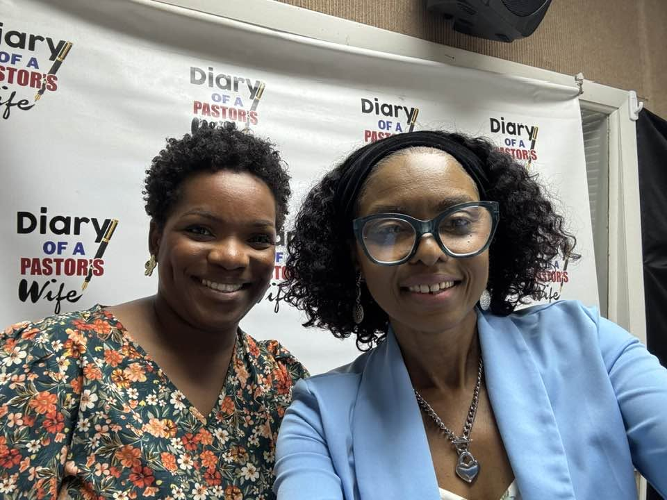 Two women smiling at Diary Talk, one in a floral blouse and the other in a blue jacket, in front of the book’s backdrop